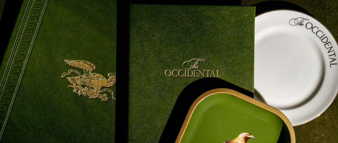 A raw steak on a white plate with brown sauce, topped with grated cheese, accompanied by a knife, fork, and a glass of red wine.